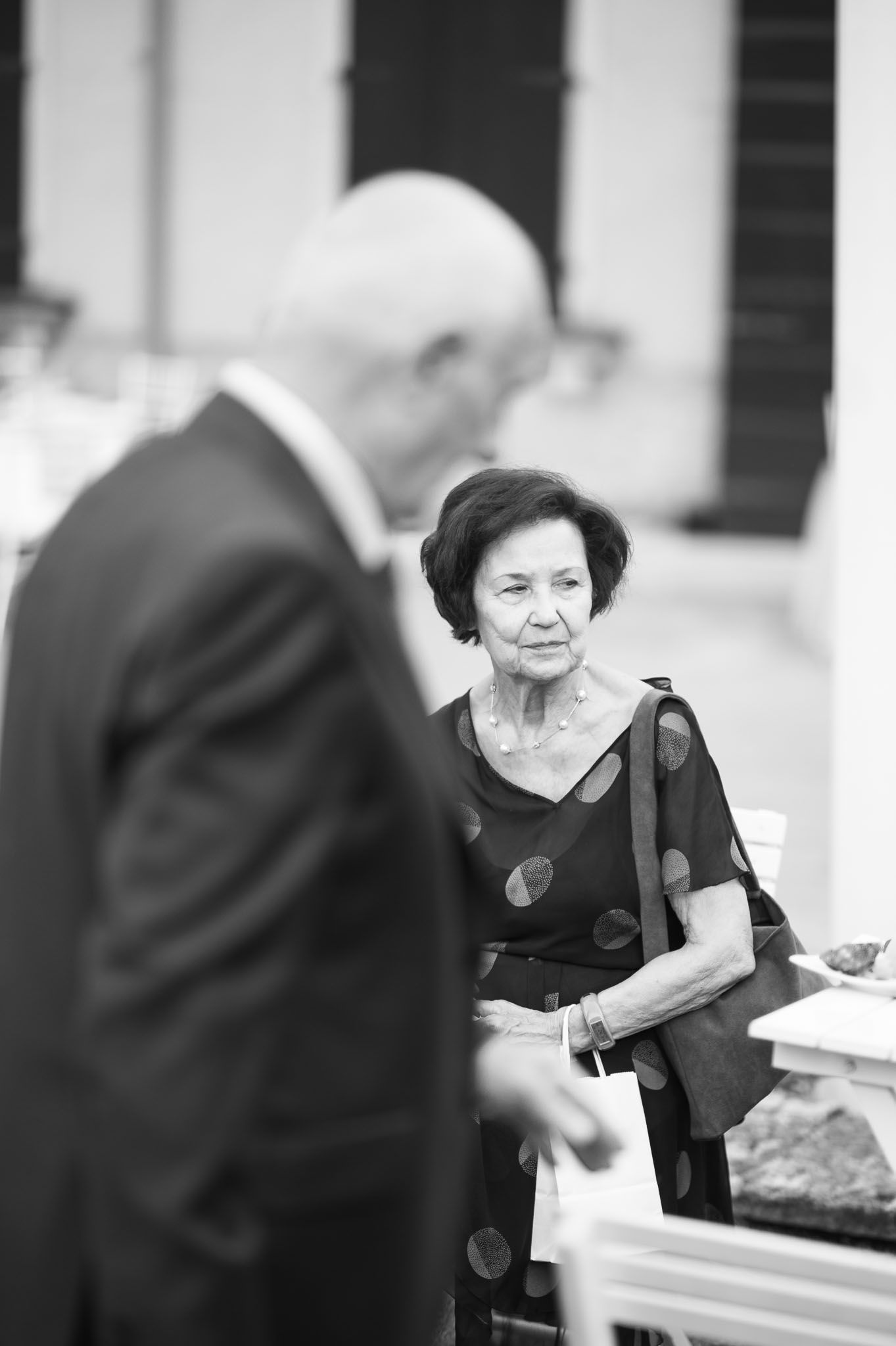 A black and white candid moment captured at a formal event with two guests in elegant attire.