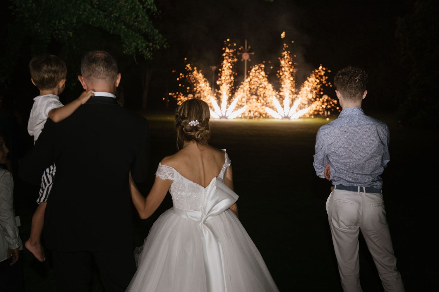 Wedding guests watch a fireworks display during an evening celebration.