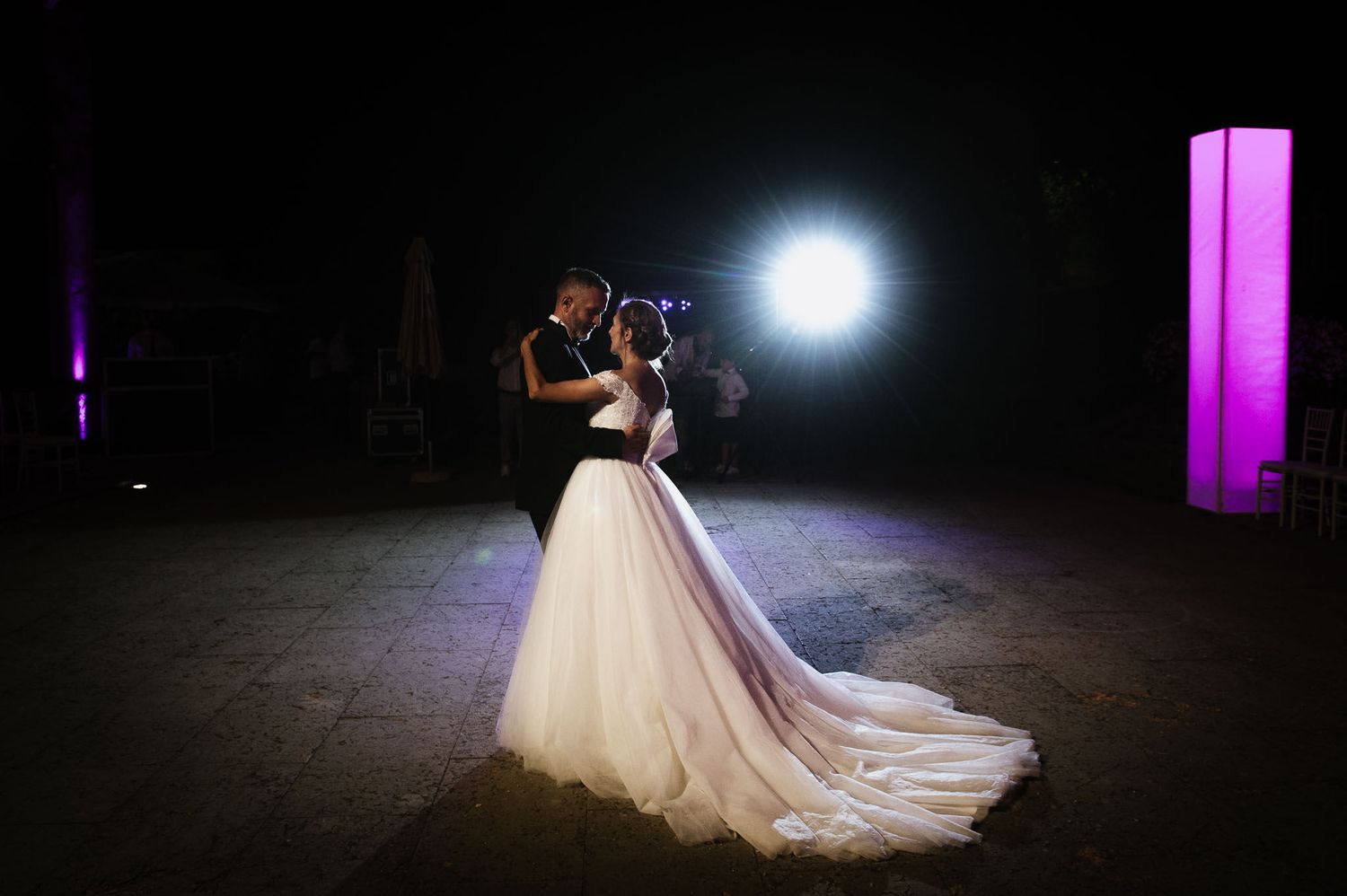 A dramatic first dance moment captured with spotlight and flowing wedding dress.