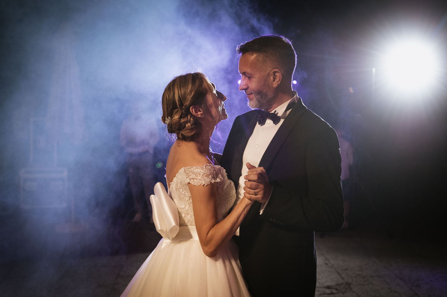 An intimate dancing moment with atmospheric smoke and dramatic lighting.