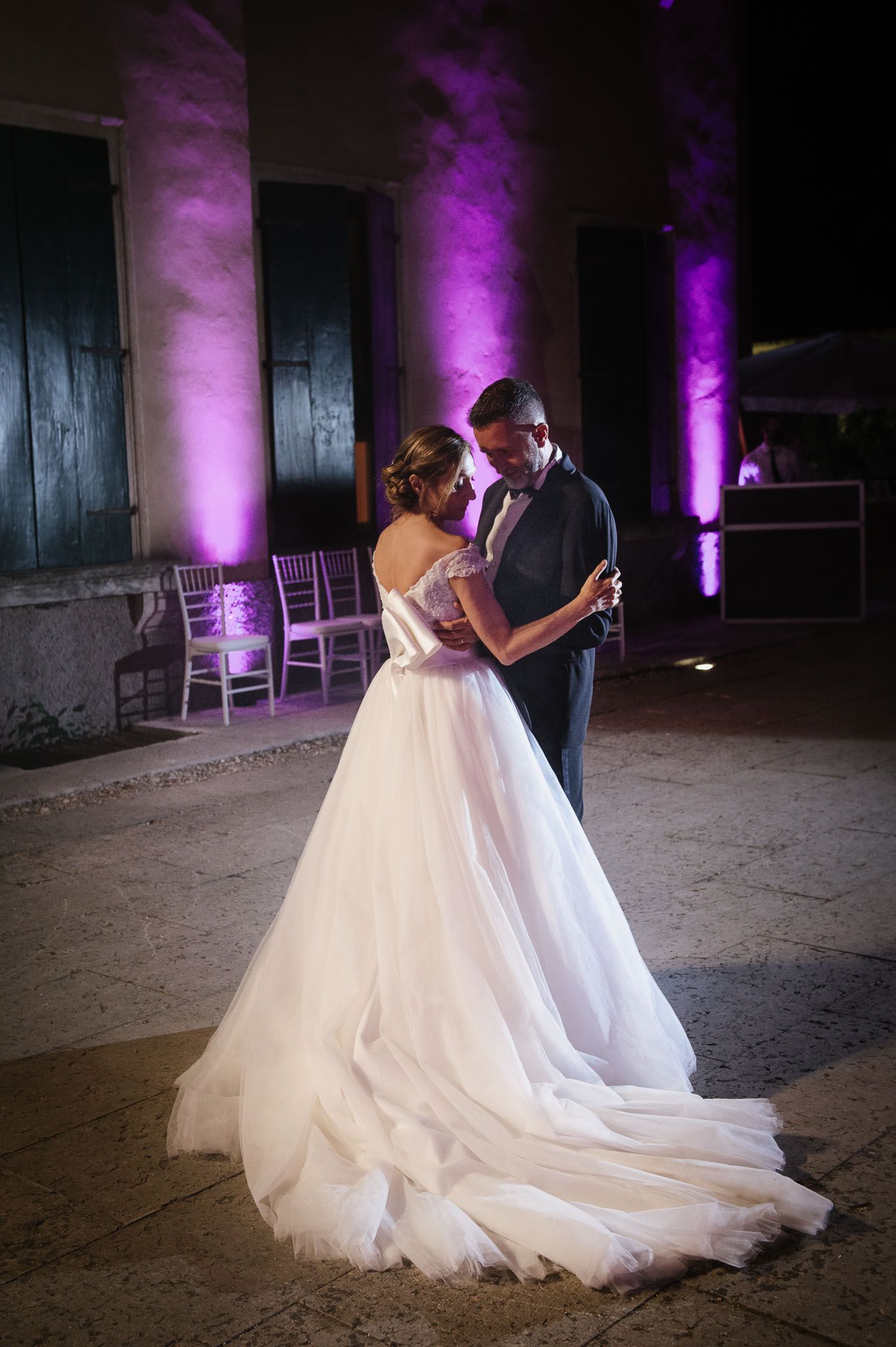 A romantic wedding dance captured against illuminated purple columns.