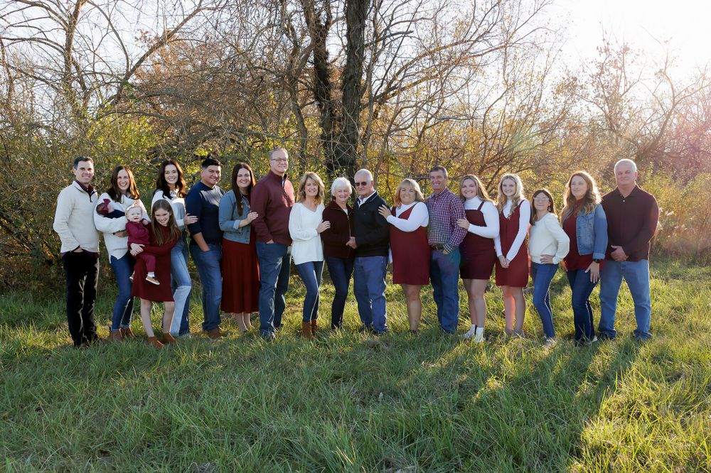 Large group photo of people dressed in burgundy and white poses together in an outdoor setting.
