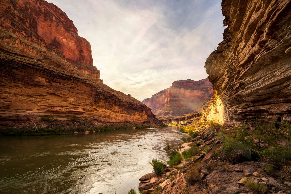 Stunning red rock canyon walls along a winding river at sunset.