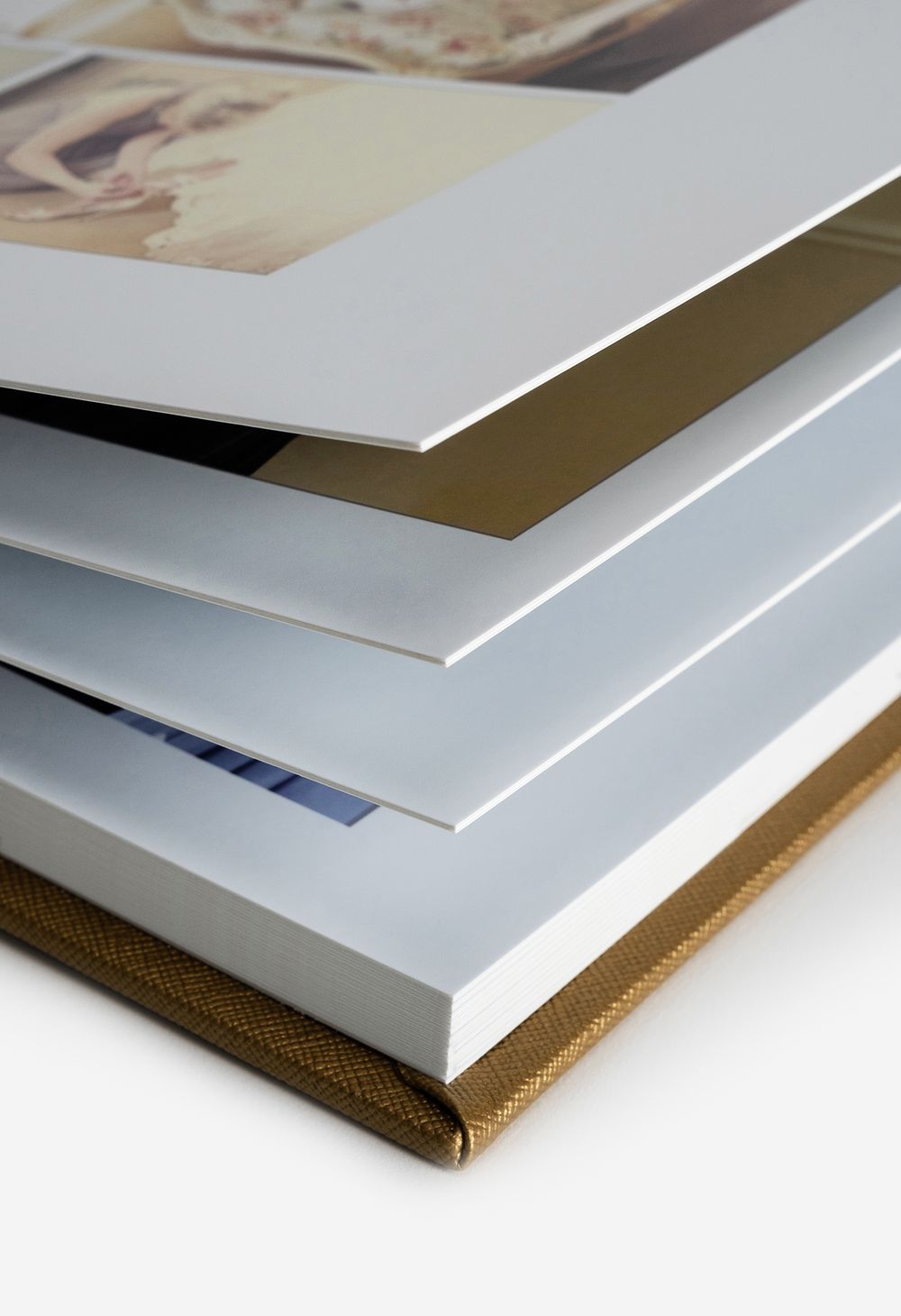 Detailed view of layered white photo album pages with gold fabric binding.