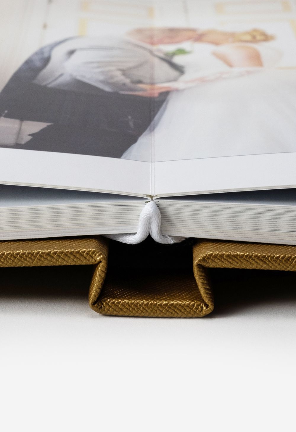 Wedding photo album open to show white pages and gold linen binding.