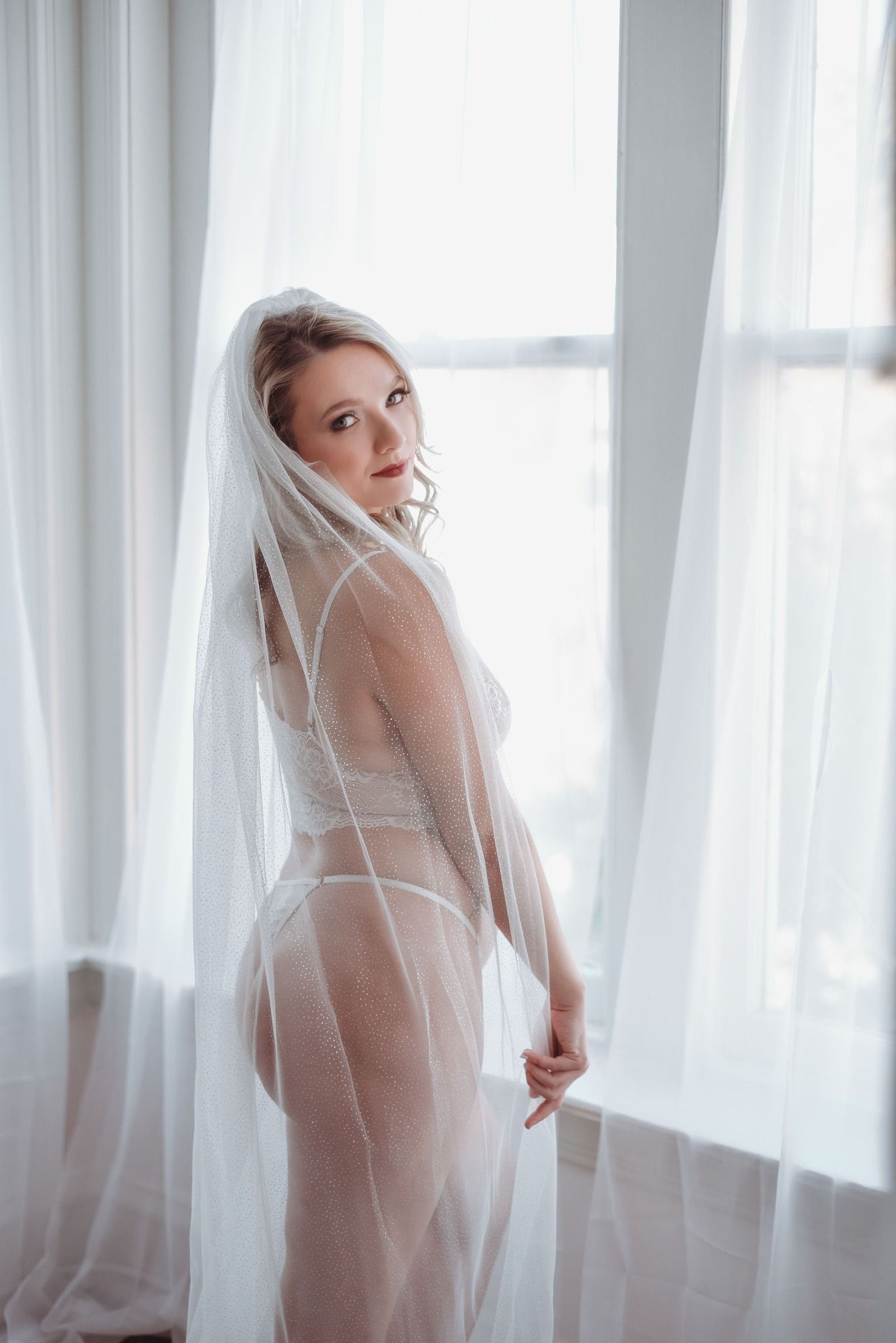Blonde woman posing for bridal boudoir session wearing her veil in downtown Cape Girardeau boudoir studio