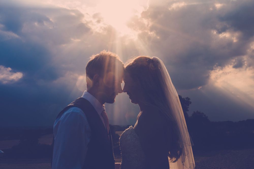 Silhouetted couple sharing an intimate moment against dramatic sunset clouds.