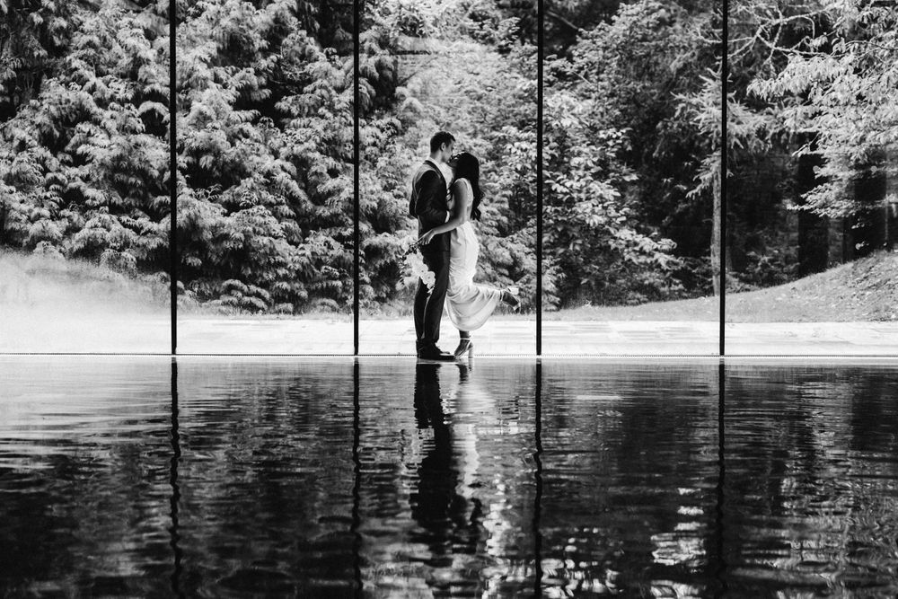 Black and white wedding Photograph bride and groom kissing at the pool with reflection