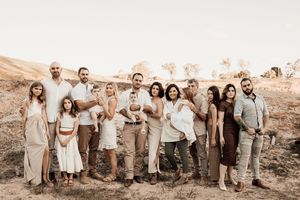 Large group posing together in neutral outfits against a desert landscape backdrop.