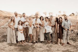 Family gathering in coordinated neutral attire standing on desert terrain.