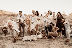 Casual group photo with people in light colored clothing having fun on desert hillside.