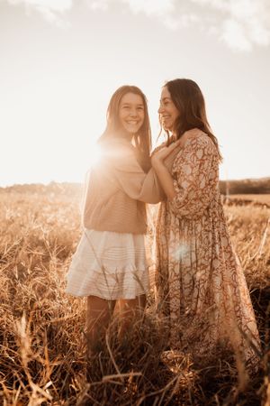 Two friends sharing joyful moment in sunlit field at golden hour.