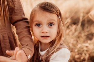 Close up portrait of young child in autumn field with warm lighting.