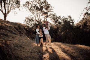 A family shares a tender moment on a hilltop path at sunset.