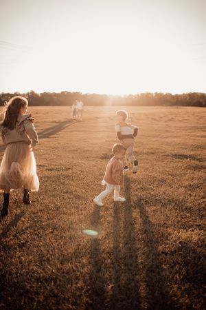 Family walking through a golden sunset field with long shadows cast across the grass.