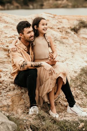 An intimate portrait of two people sitting together on rocky terrain in matching neutral tones.