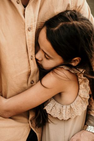 A close-up emotional embrace captured in warm natural lighting with soft neutral tones.