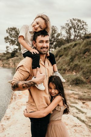 Family enjoying playful moment together on sandy beach path in warm sunlight.