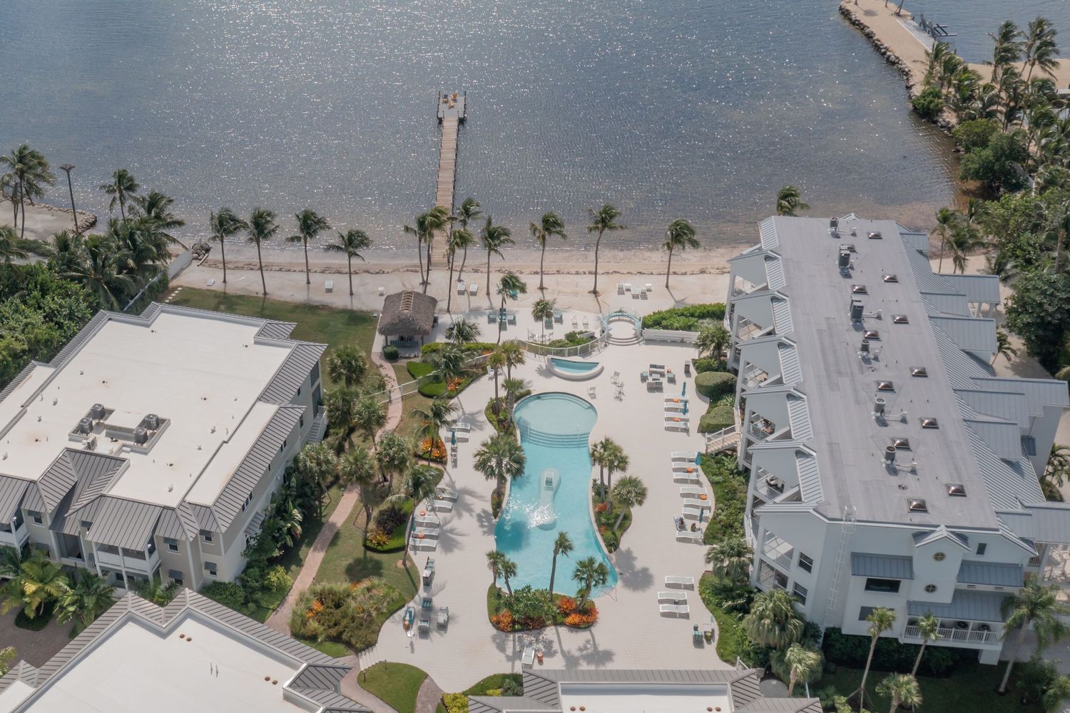 Aerial view of beachfront resort property with pools and palm trees.