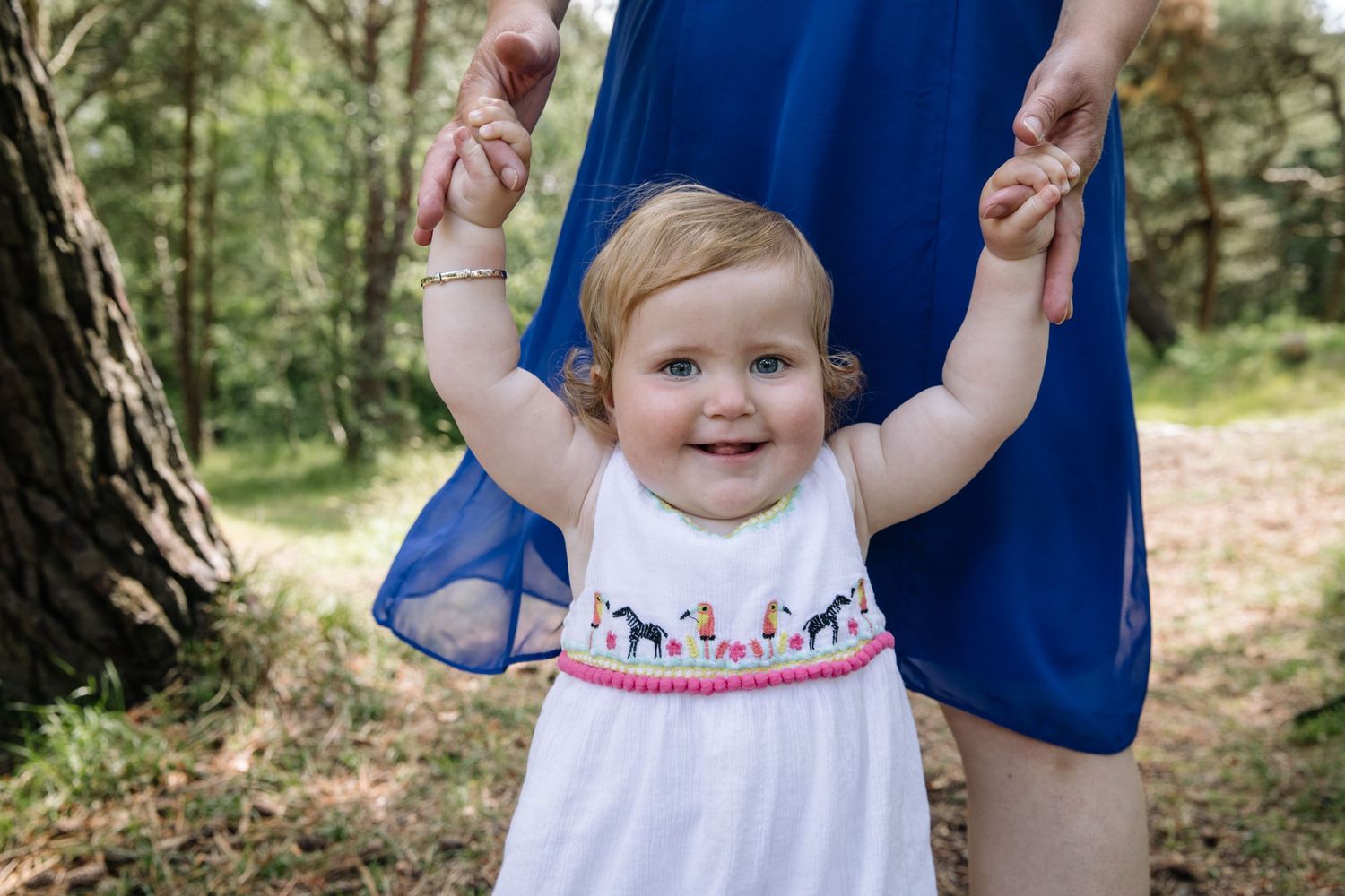 A white summer dress with embroidered details is worn during a forest walk.