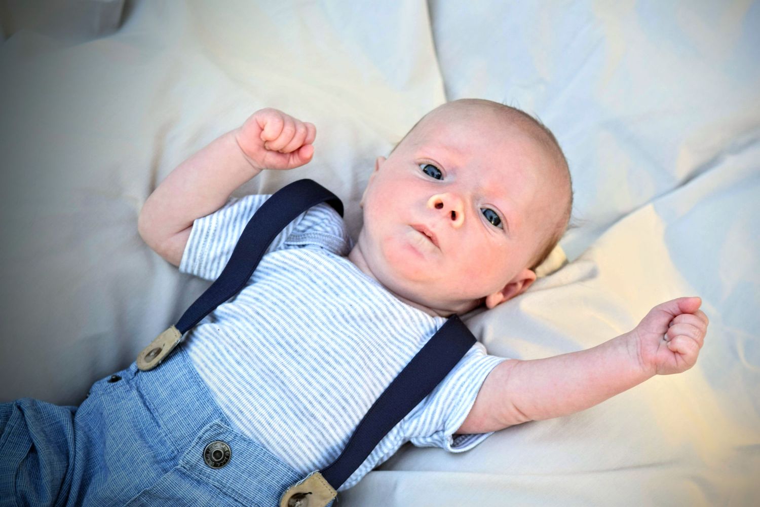 Newborn lifestyle session. Baby boy in suspenders.