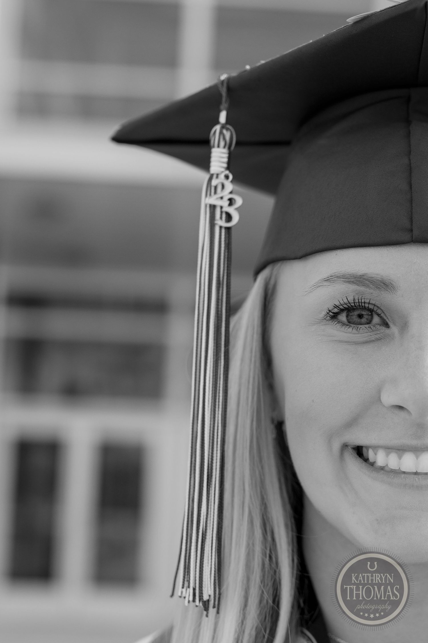 Close-up black and white photo of graduation cap tassel against blurred background.