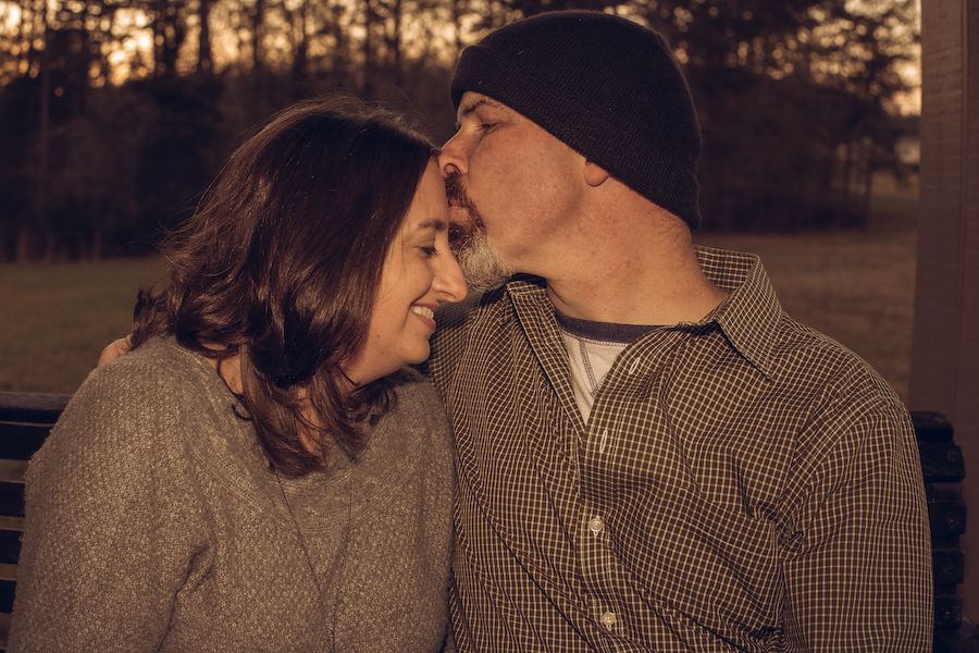 A romantic couple sharing an intimate moment at sunset wearing casual clothing.