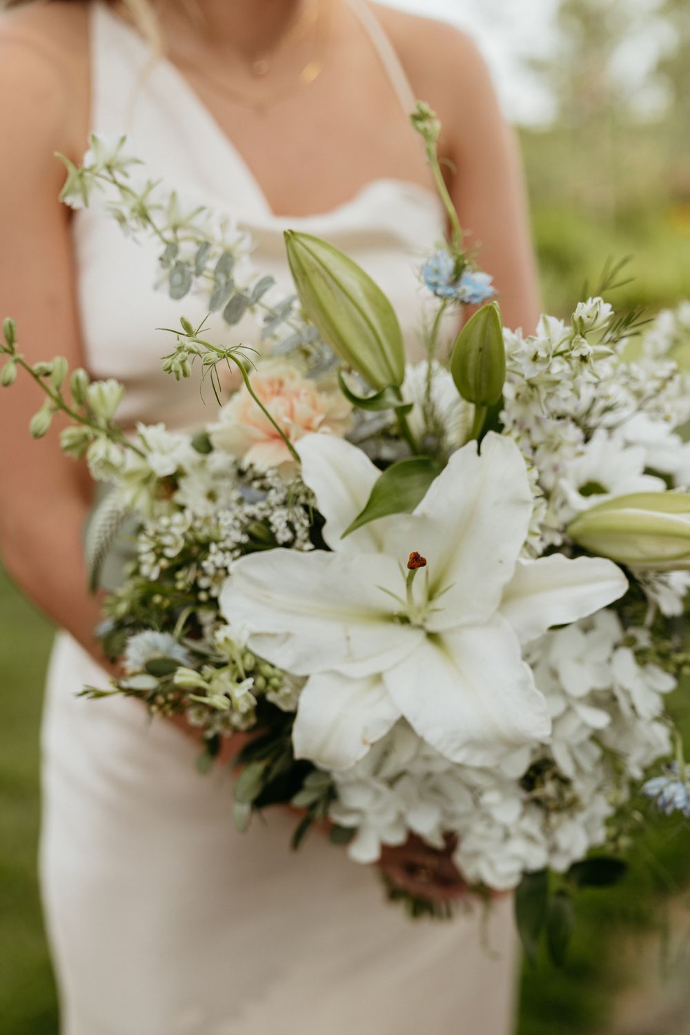 A beautiful white lily and floral wedding bouquet with delicate greenery.