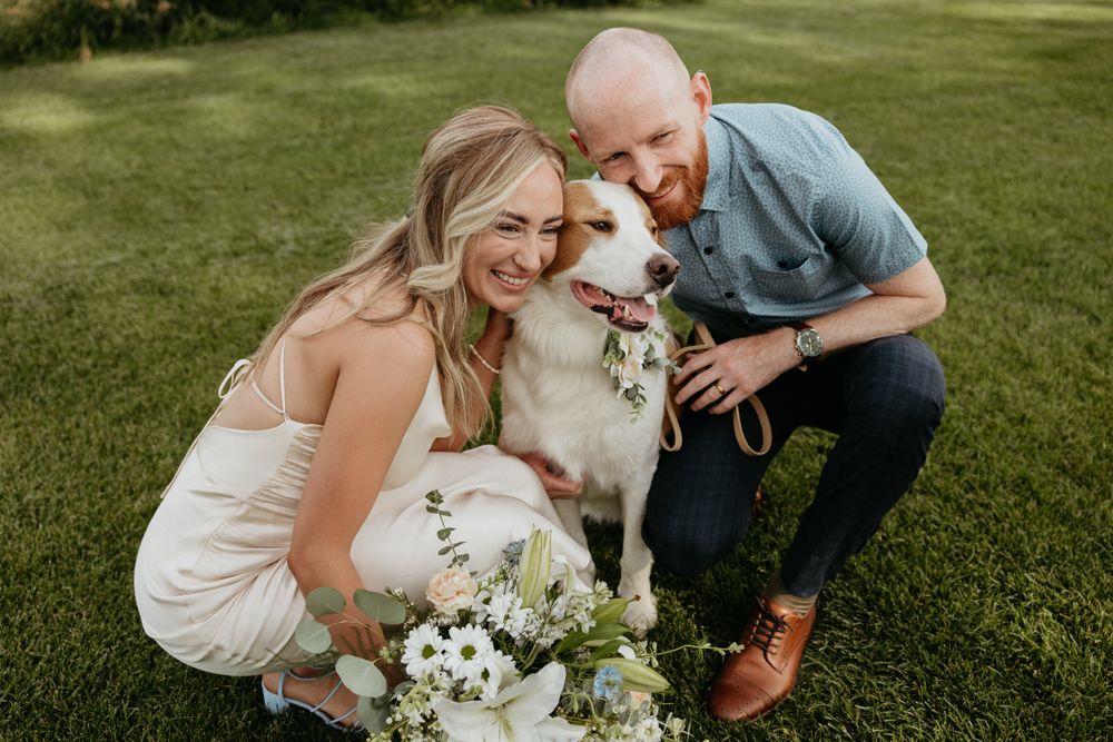 A white dog joins a couple during their outdoor photo session.
