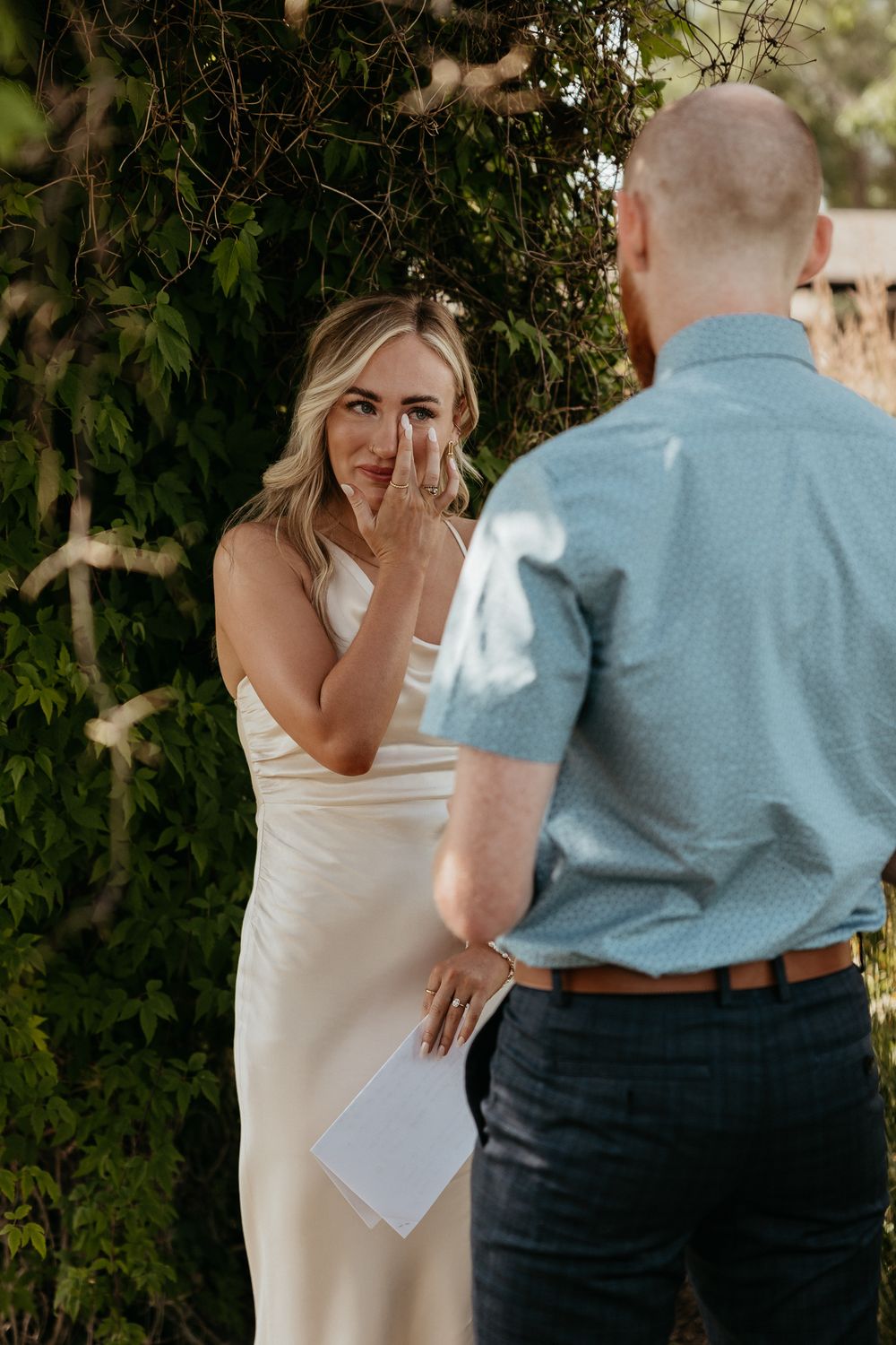 Two people share emotional vows during an intimate outdoor ceremony.