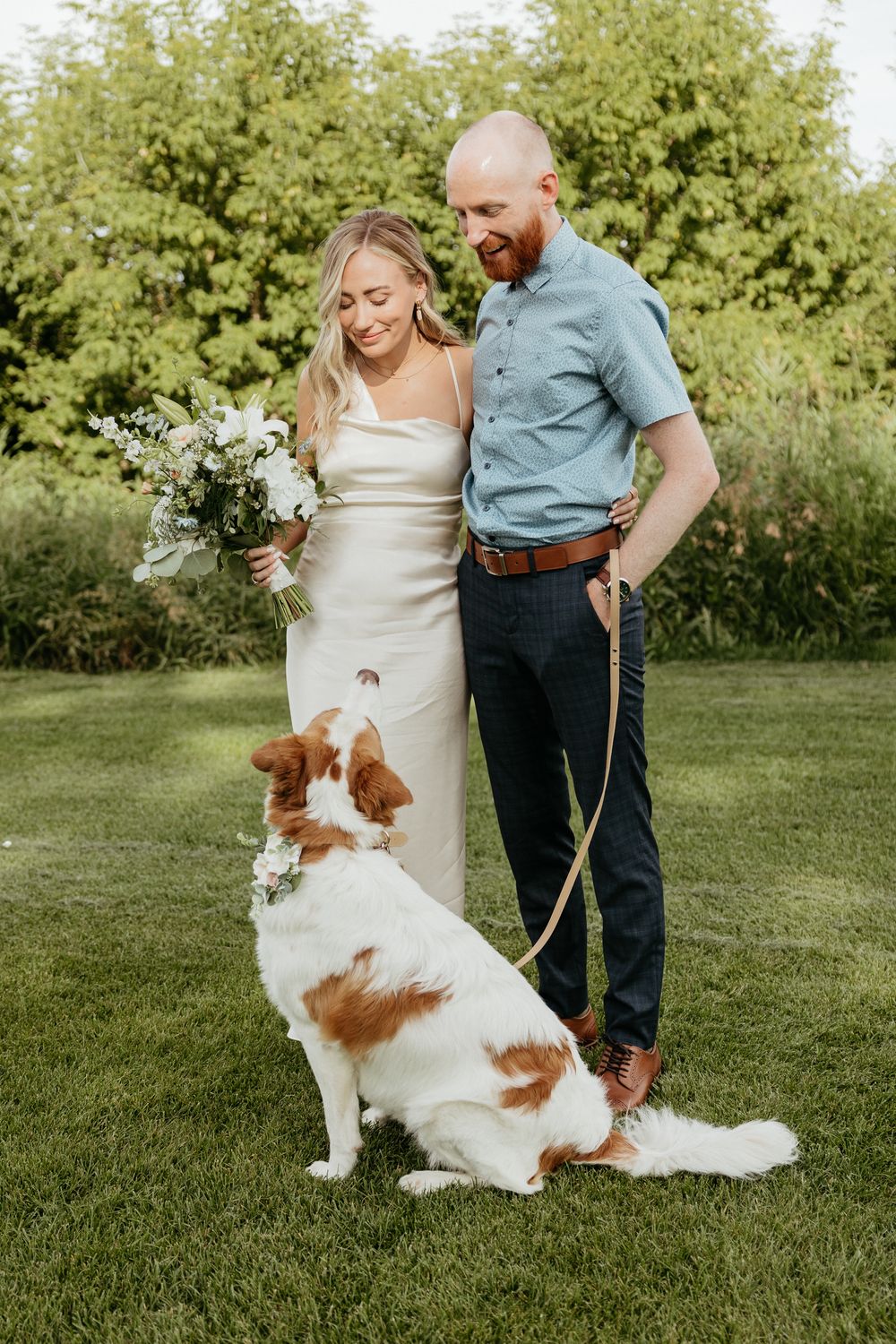 A couple poses with their happy dog during an outdoor photo session.