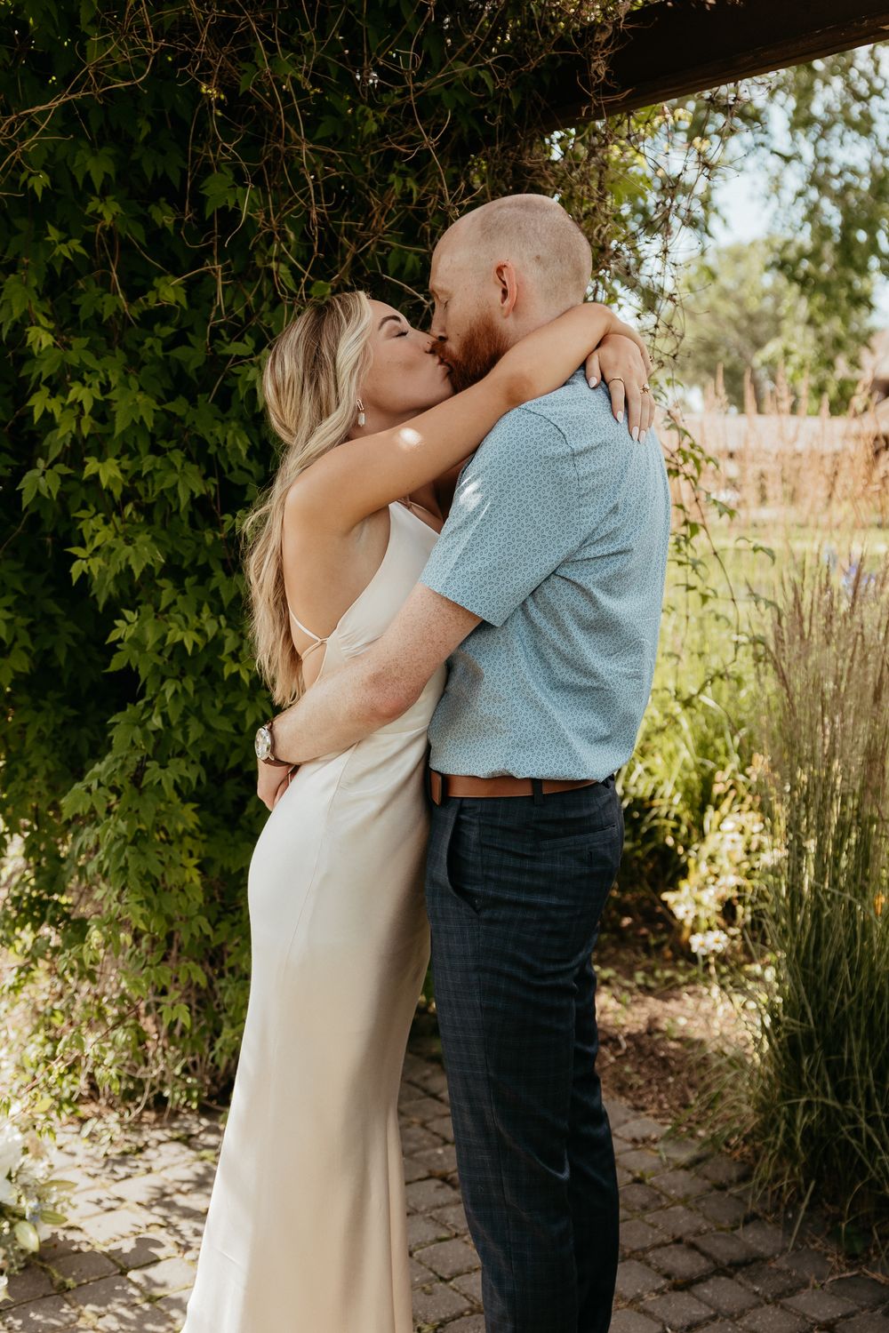 A couple embraces tenderly during their outdoor garden ceremony.