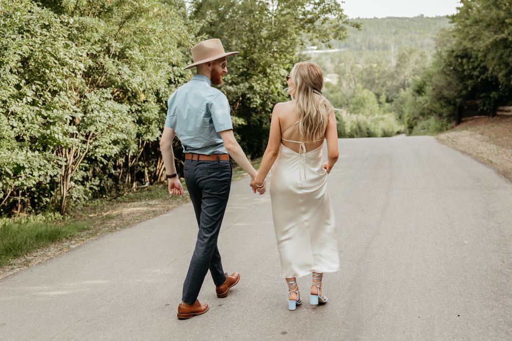 A couple walks away together on a tree-lined country road.