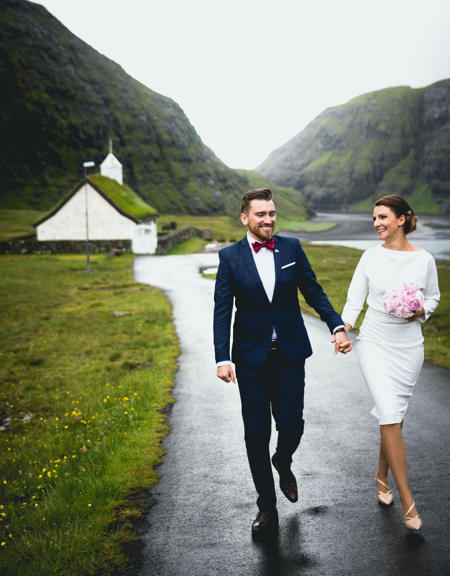 Brudepar går fra kirken smilende efter vielse, flot landskab