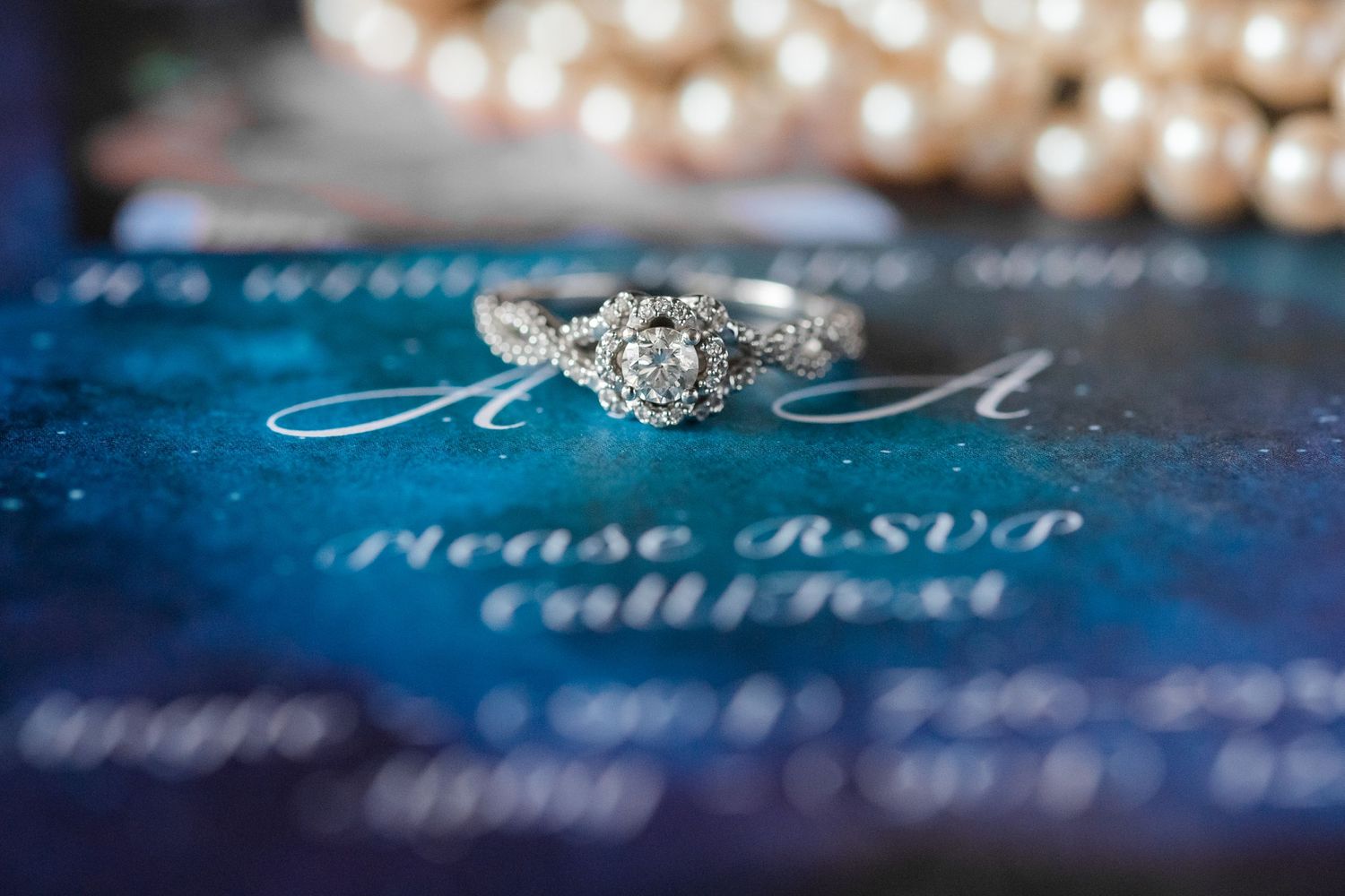 Elegant wedding jewelry and rings arranged on blue stationery with sparkly details.