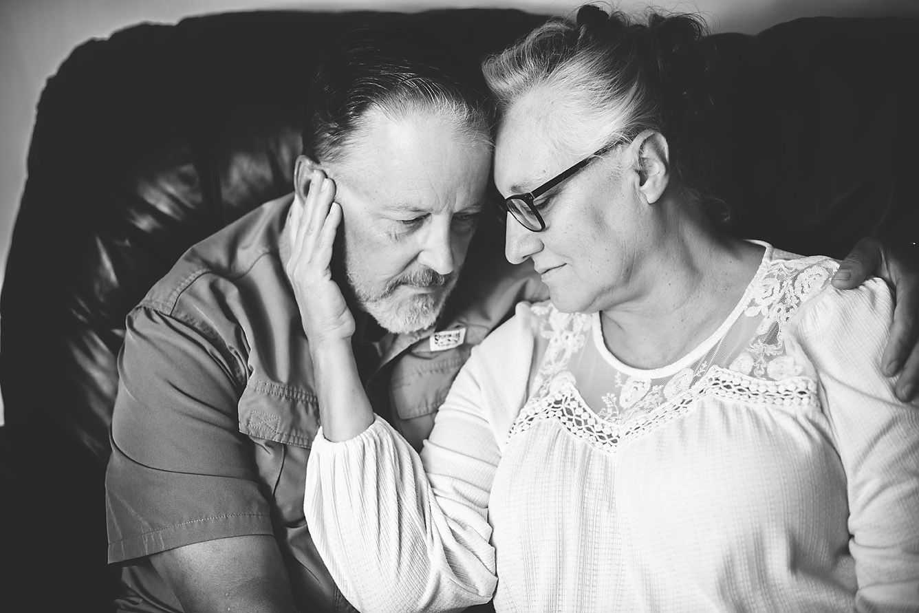 Black and white photo of an older couple sharing an intimate moment, touching foreheads tenderly.