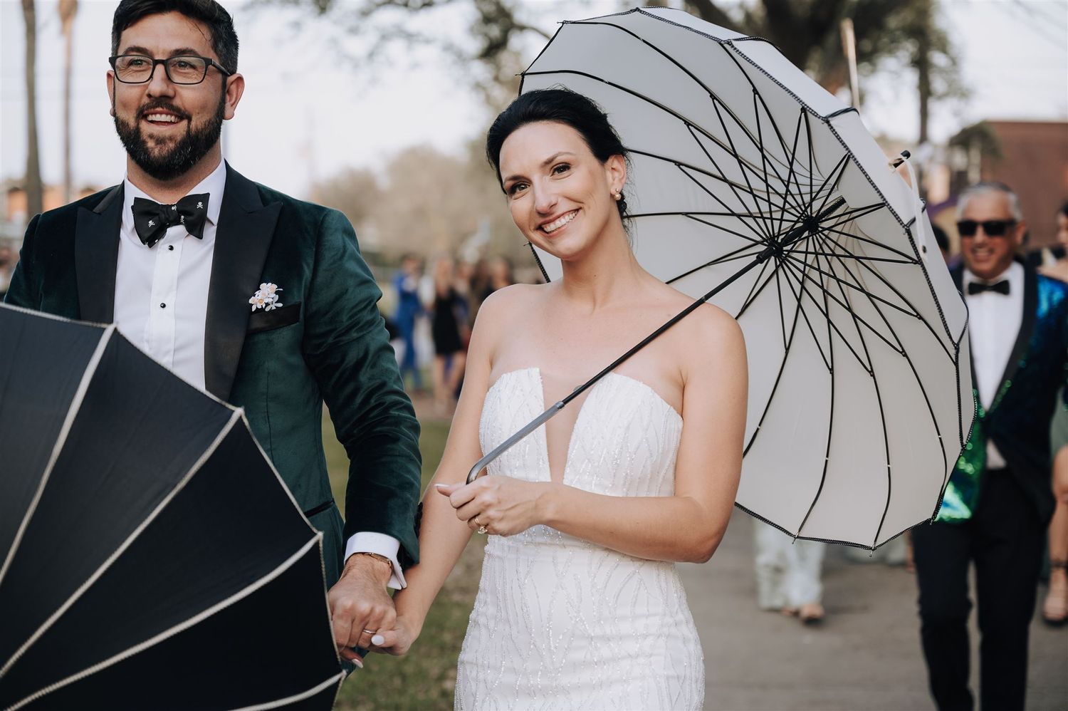 A couple poses with elegant black and white parasols at their outdoor wedding.
