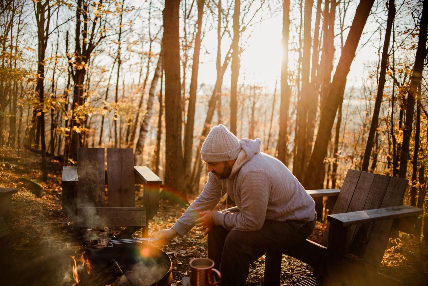 Someone in casual wear resting on wooden bench surrounded by sunlit autumn forest.