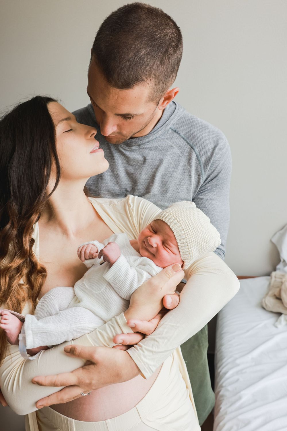 Intimate portrait of parents sharing a loving moment while holding their newborn baby.