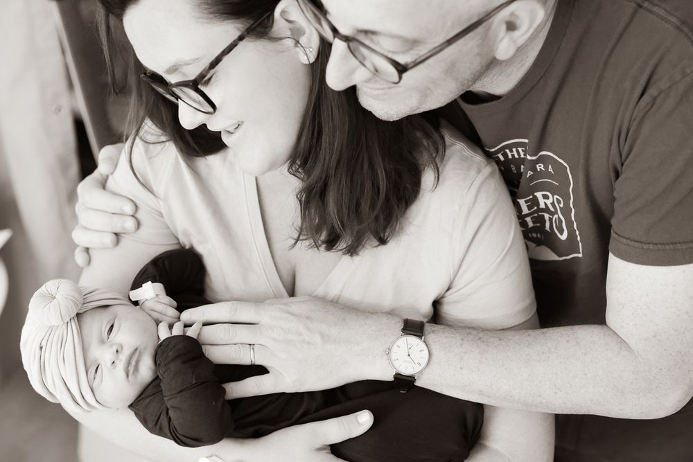 Black and white portrait of parents gazing lovingly at their newborn.