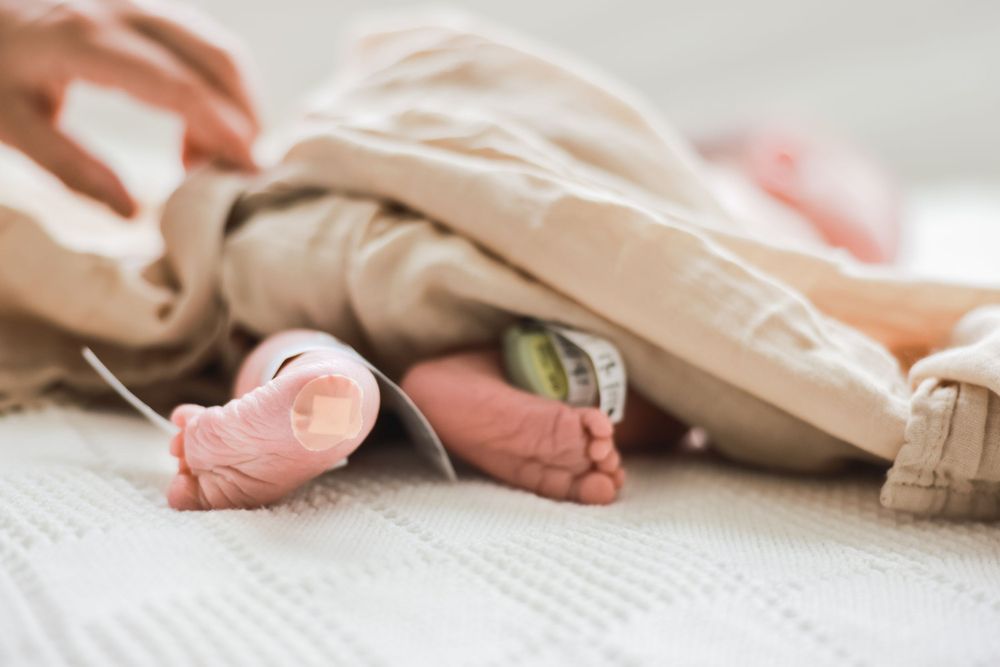 Tiny newborn feet peeking out from under a beige blanket.