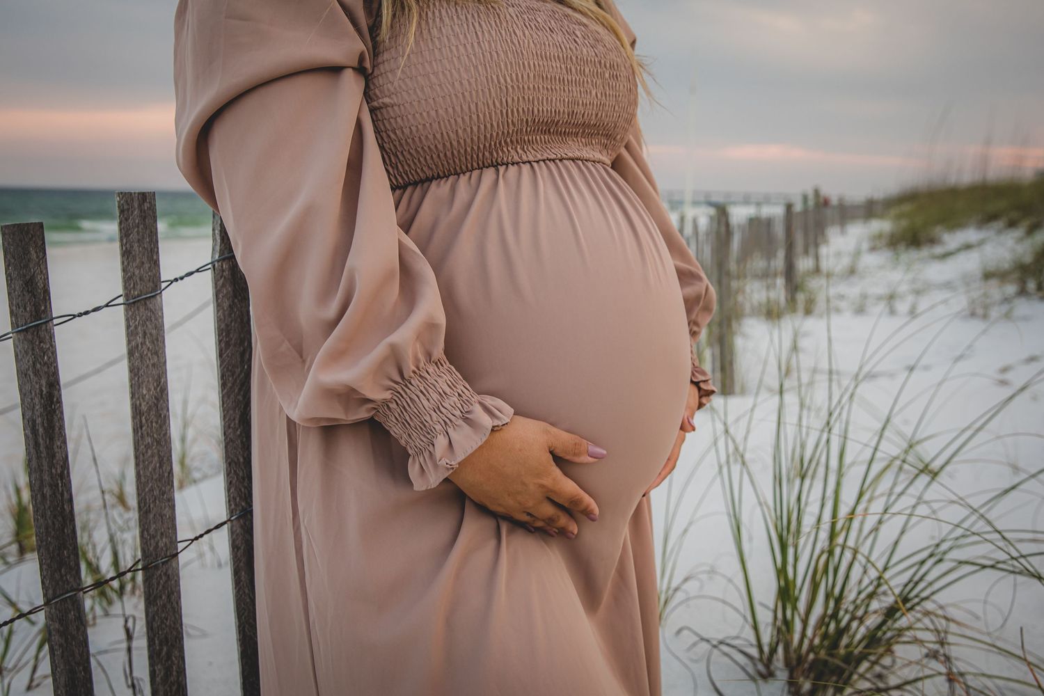 Maternity photography series showing pregnant woman in blush dress at sunset.