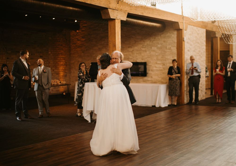 Bride shares a heartfelt dance with an older family member at rustic wedding reception.