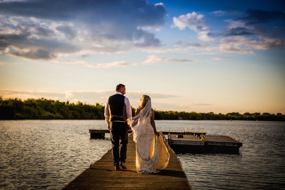 Bride & Groom walking into sunset along a jetty