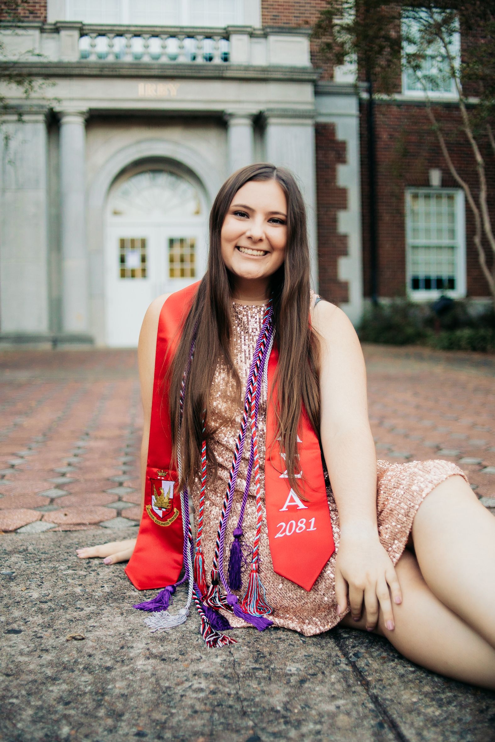 female graduate sitting on ground smiling