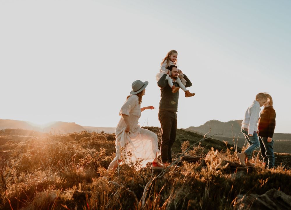 Silhouettes of people walking along a hilltop during golden hour sunset.