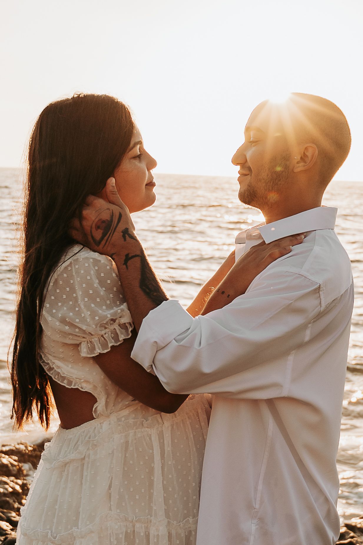 Romantic sunset beach portraits of couple in white attire.