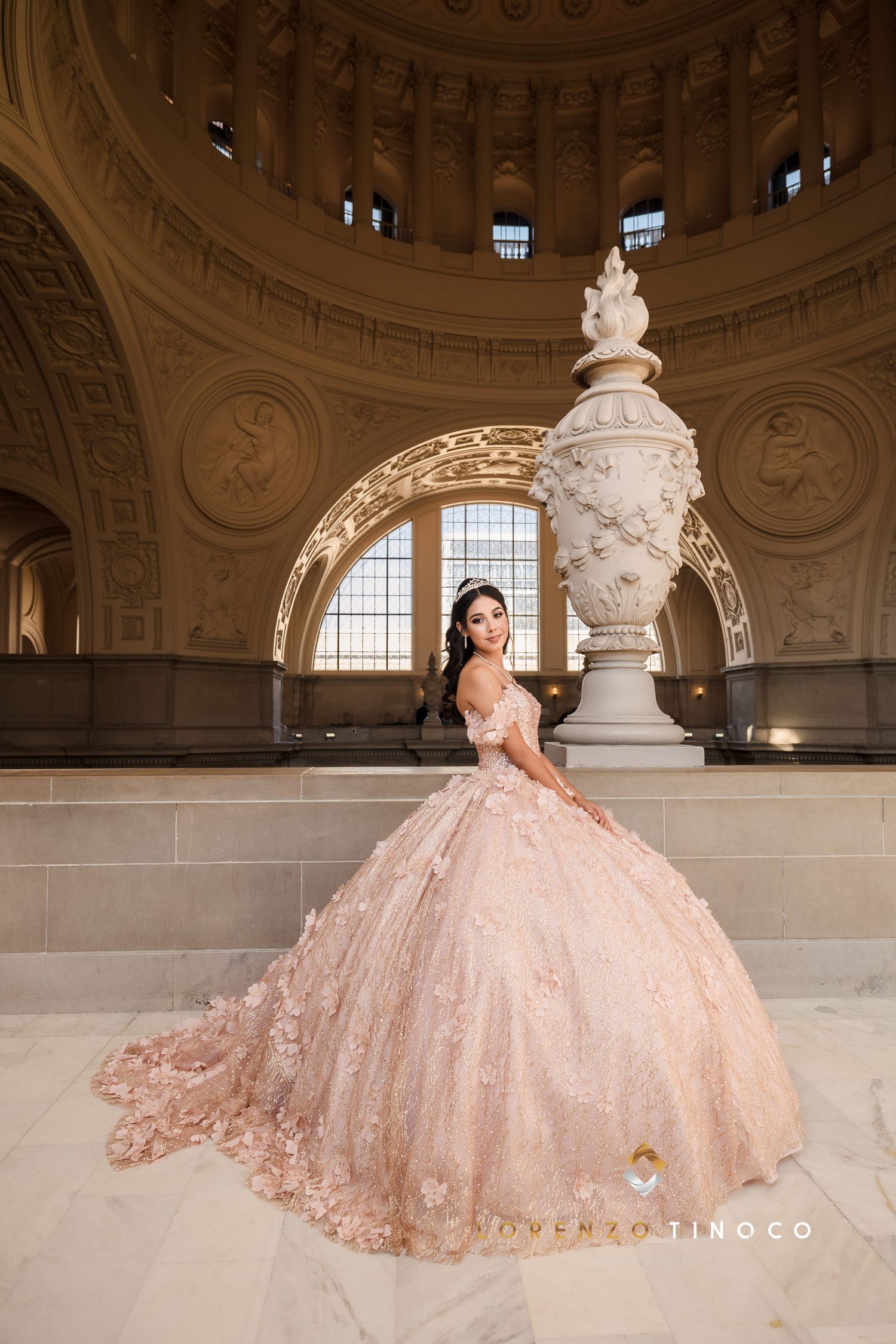 A stunning blush gown with long train photographed in a classical rotunda with decorative sculpture.