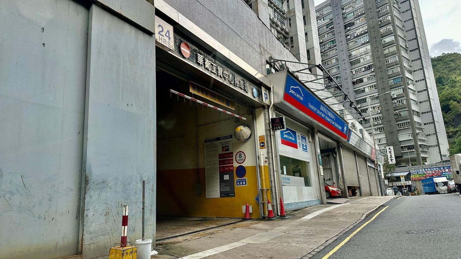 Street view of a commercial building entrance with gray walls and metal security gates.