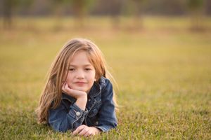 Portrait of youth lying on grass wearing denim jacket in natural outdoor setting.
